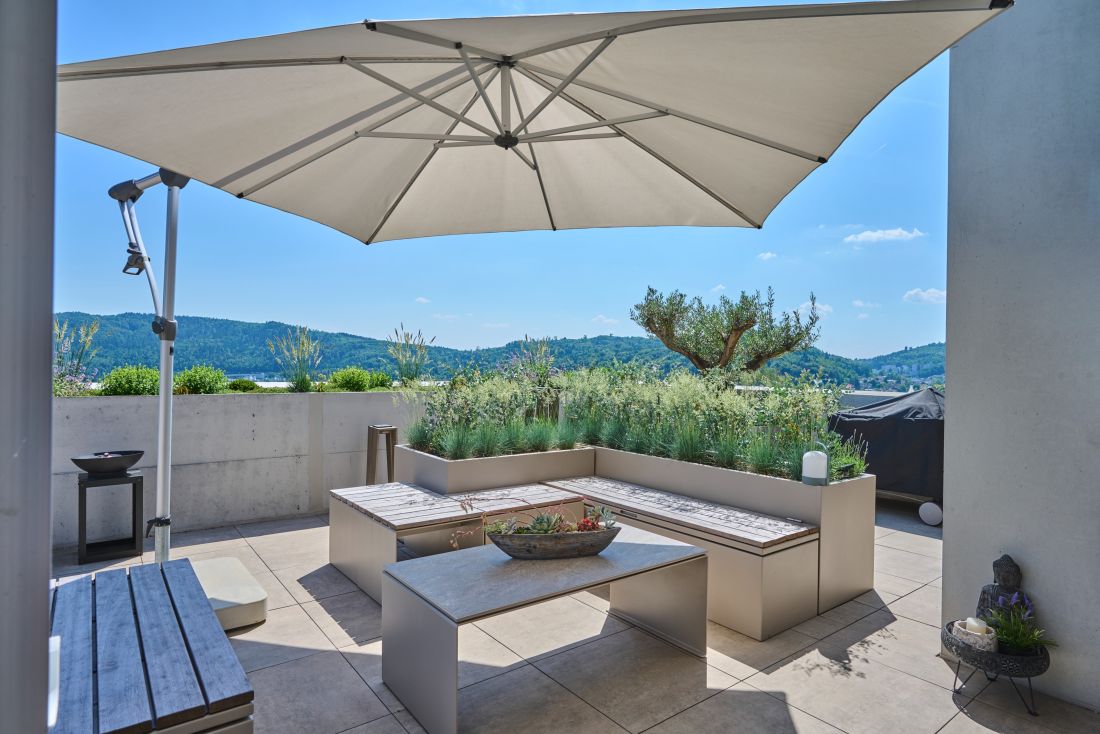 Moderne Terrassengestaltung mit Sitzbank, Pflanzen und Sonnenschirm, Gartenbau Aargau von Schoop Gartenbau