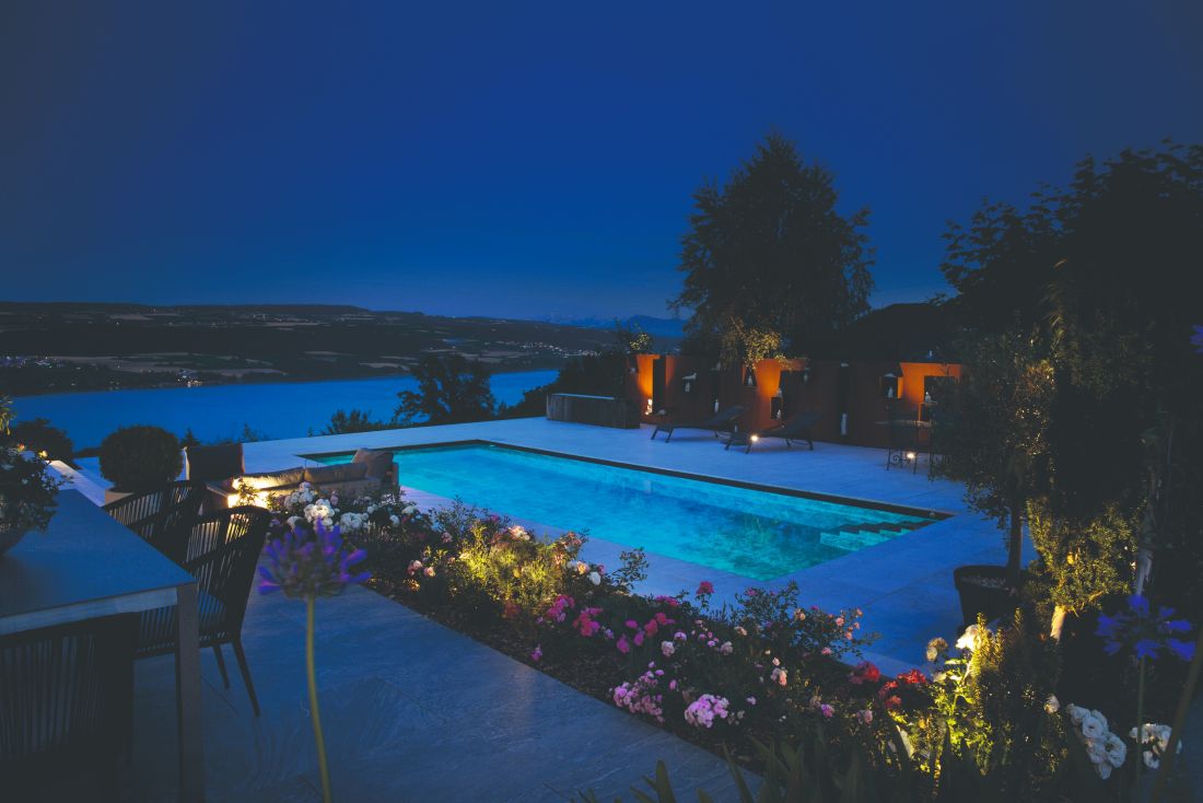 Beleuchteter Pool bei Nacht, Blumenbeet und Aussicht, Gartenbau Aargau von Schoop Gartenbau