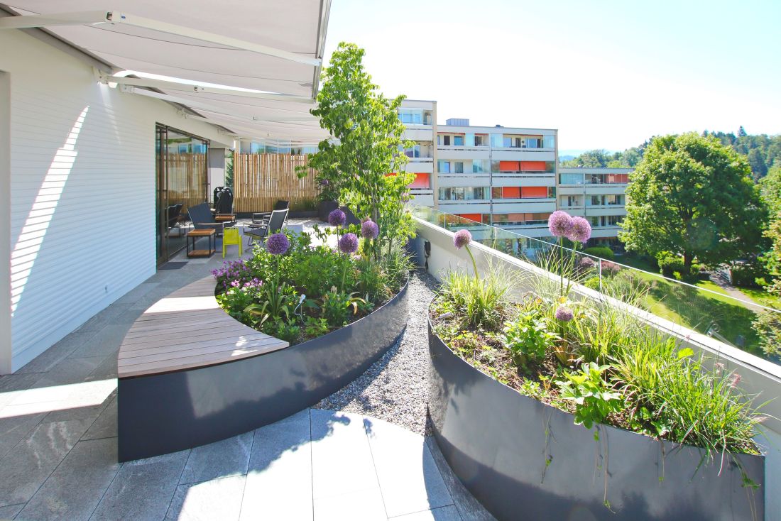 Moderne Terrasse mit Sitzbereich und bepflanzten Hochbeeten bei Schoop Gartenbau Aargau