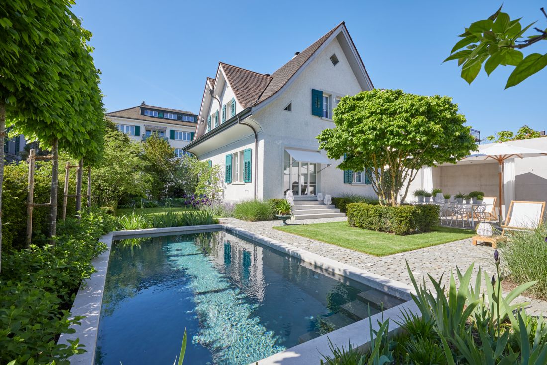 Moderner Gartenbau Aargau mit Schwimmteich, gepflegtem Rasen und Sitzplatz von Schoop Gartenbau