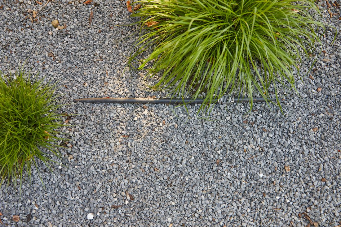Automatisches Bewässerungssystem mit Tropfrohr und grünen Pflanzen auf Kiesboden Gartenbau Aargau Schoop