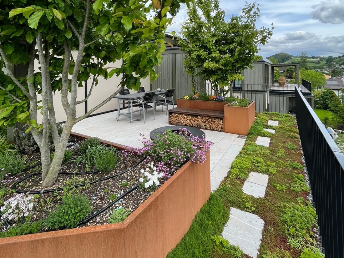 Moderne Terrasse mit automatischem Bewaesserungssystem, bepflanzten Hochbeeten und Gartenpflege von Schoop Gartenbau Aargau