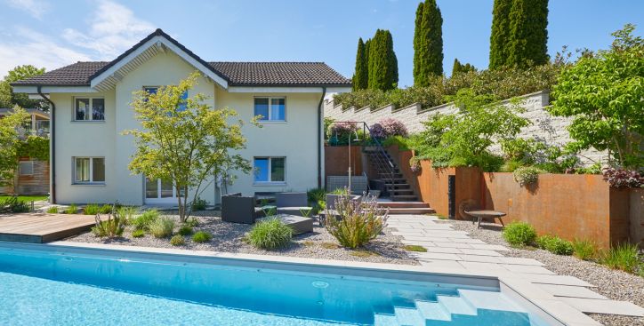 Einfamilienhaus mit Pool und moderner Gartenanlage, Sitzplatz mit Sträucher, bepflanzte Hochbeete aus Metall in Rostoptik
